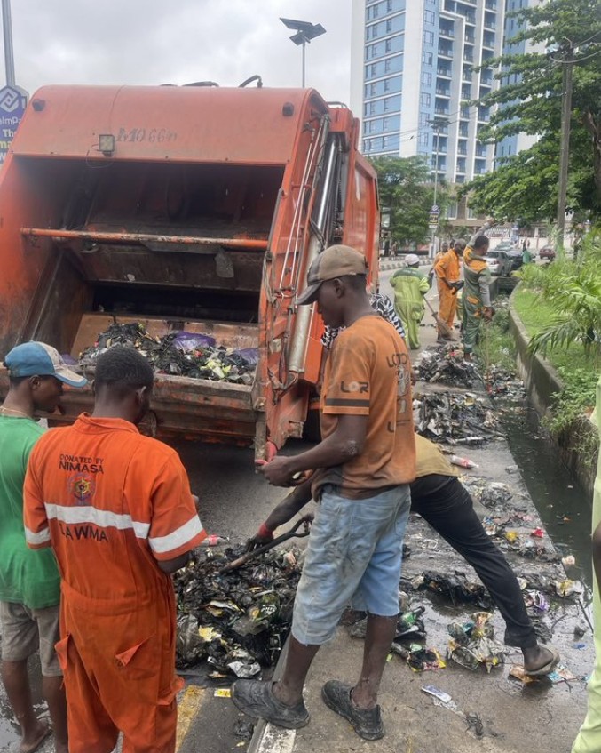 7 operatives of the Lagos State Waste Management Authority (LAWMA) cleaning up a drainage channel and disposing the waste in a waste disposal truck