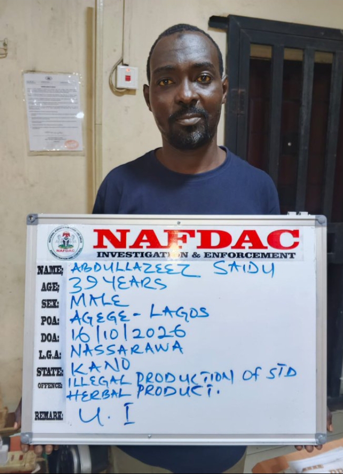 A man in a navy blue shirt, holding a NAFDAC board containing his details